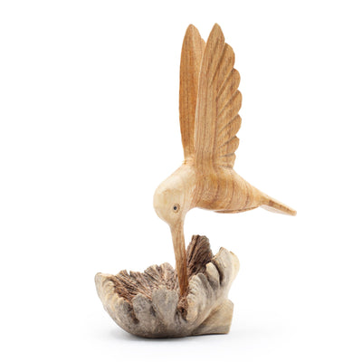 Escultura hecha a mano de un colibrí bebiendo néctar de un nudo de madera