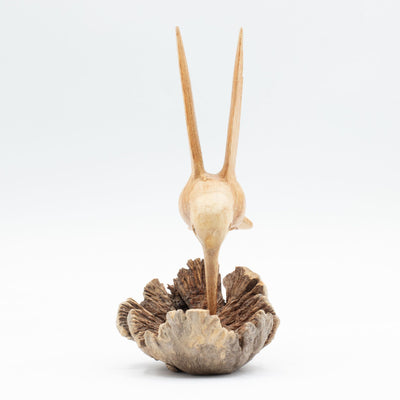 Escultura hecha a mano de un colibrí bebiendo néctar de un nudo de madera