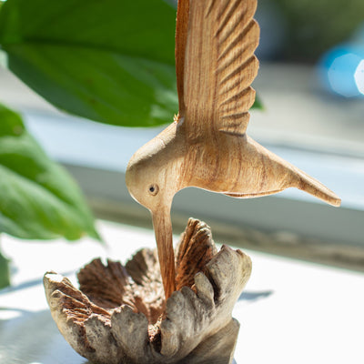 Escultura hecha a mano de un colibrí bebiendo néctar de un nudo de madera